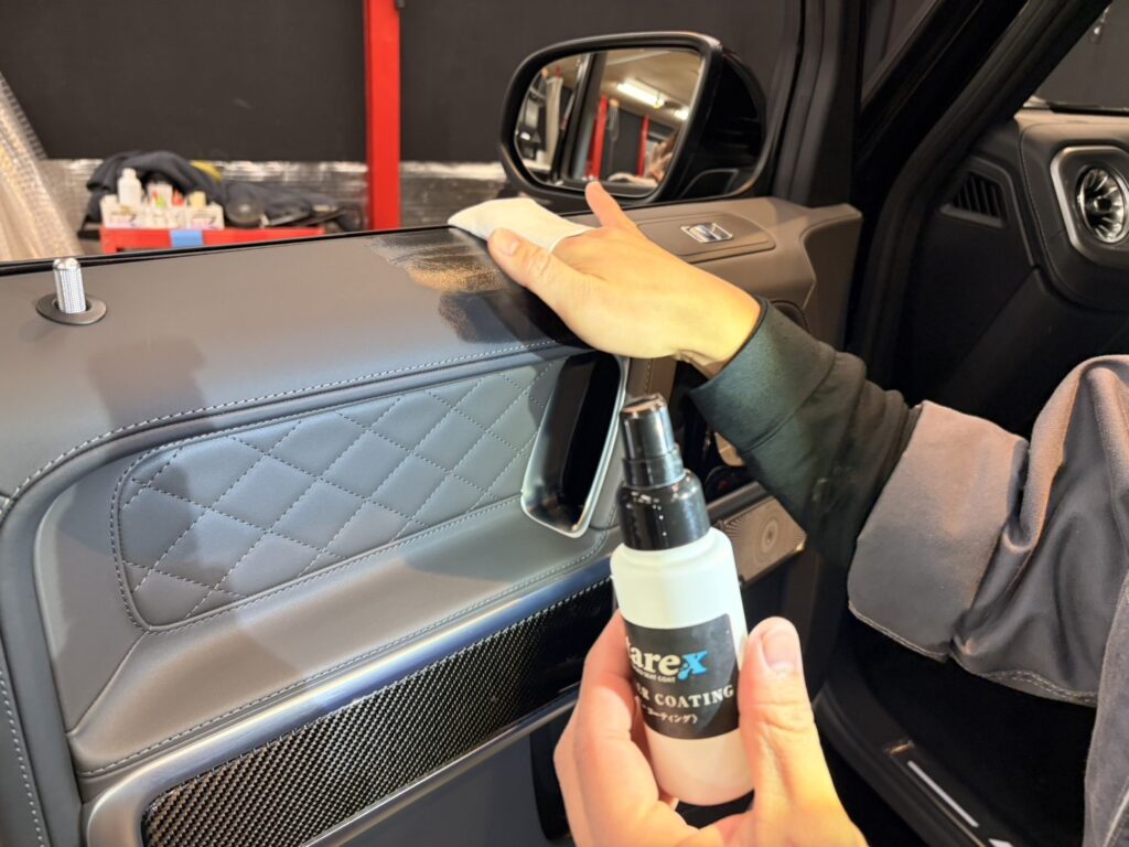 ひし形ステッチのドア内張りの上側にクロスで液を塗る手元