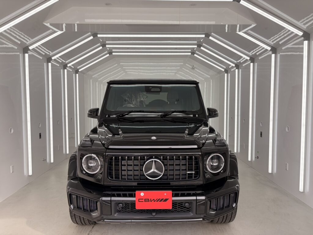 照明のブースに入った黒いメルセデスAMG G63の正面