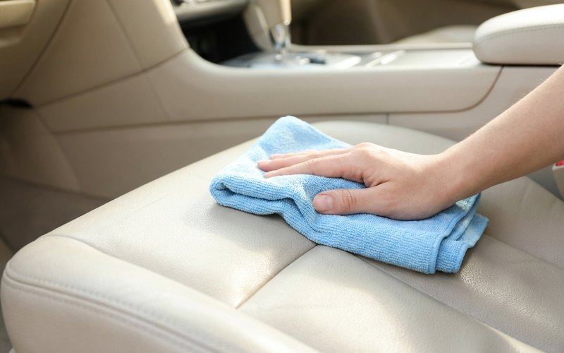 車のシートをマイクロファイバークロスでやさしく拭くお手入れの様子