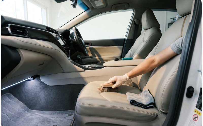 Car Detailing BECSELの作業カット。本革シートの座面外側の縁とサイドサポートを、革の状態を確かめながら丁寧に洗浄しているところ