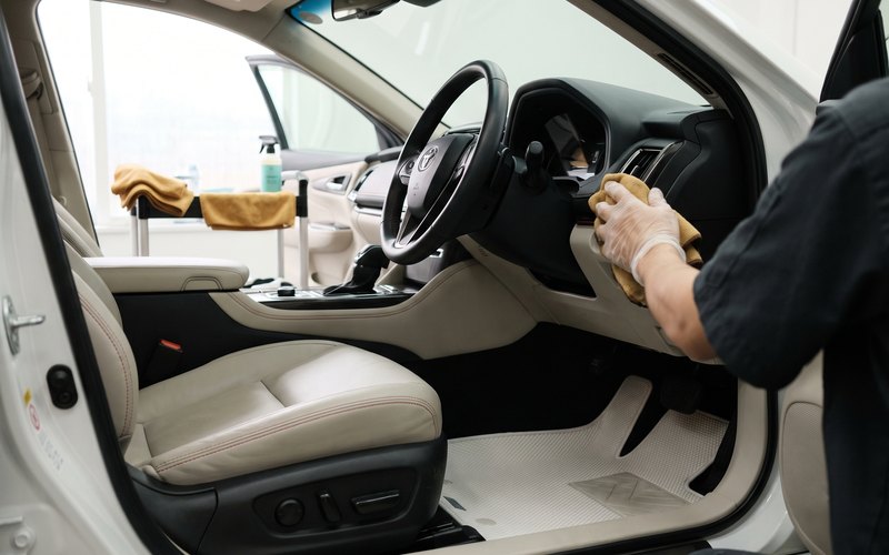 Gloss上田の作業ブースで、運転席をフルスライドさせ、ドア側の座面の角とサイドサポートの擦れを確認しながら洗浄している様子