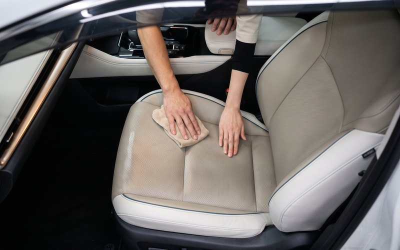 洗浄を終えた運転席のシート生地へ水性シートコーティングを施工している場面