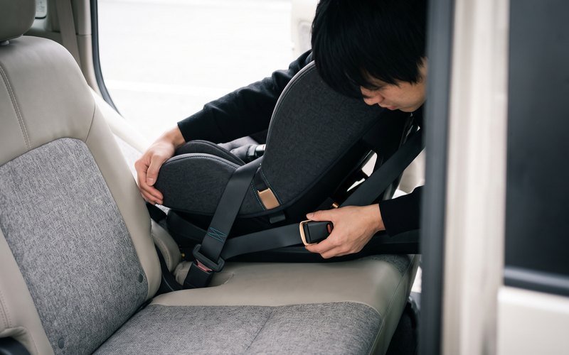 洗浄を終えた後席のチャイルドシート設置面へ、Carglanz(カーグランツ)が水性シートコーティングをむらなく施工している場面