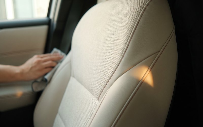 洗浄を終えた中古車のシート表面に水性シートコーティングを施工している様子