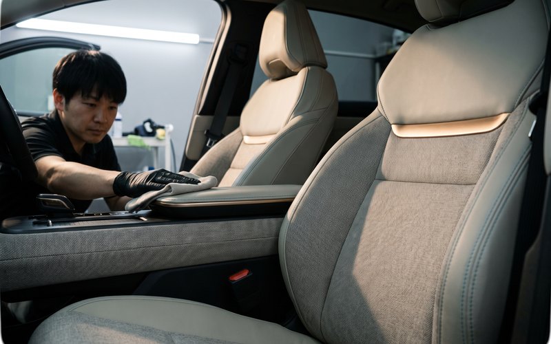 株式会社フレスコ(フレッシュカーサービス)での作業。軽自動車の運転席背もたれと、隣接するドアトリムの布部分を専用機材で洗浄している様子