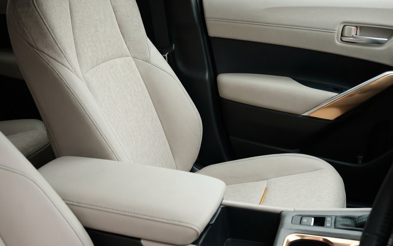 洗浄を終えた軽自動車のシート生地に、フレッシュカーサービスのスタッフが水性シートコーティングを塗り込んでいる場面