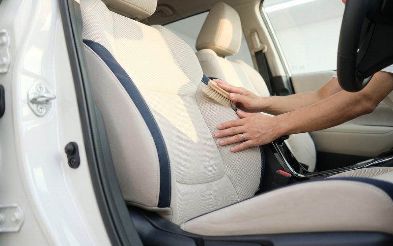 洗浄後の運転席シートへ水性シートコーティングを塗り広げている施工の様子