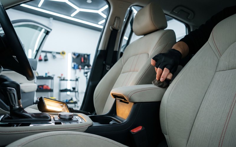 大口町の有限会社メーキングファクトリーポリッシュで、軽自動車のファブリックシート全体を専用機材で洗浄している作業風景