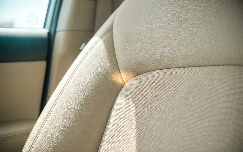 洗浄を終えた本革シートへ、得洗隊 株式会社のスタッフが水性シートコーティングをシボに沿って施工している場面