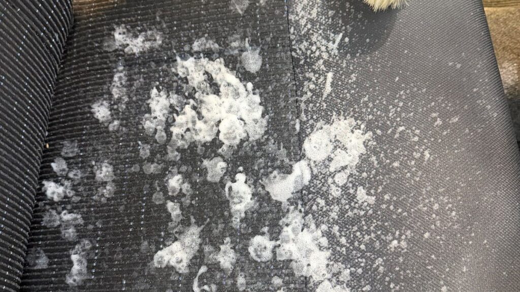 ダイハツ ムーヴカスタムの布シートに洗浄剤の泡をのせ、ブラシを置いたところ